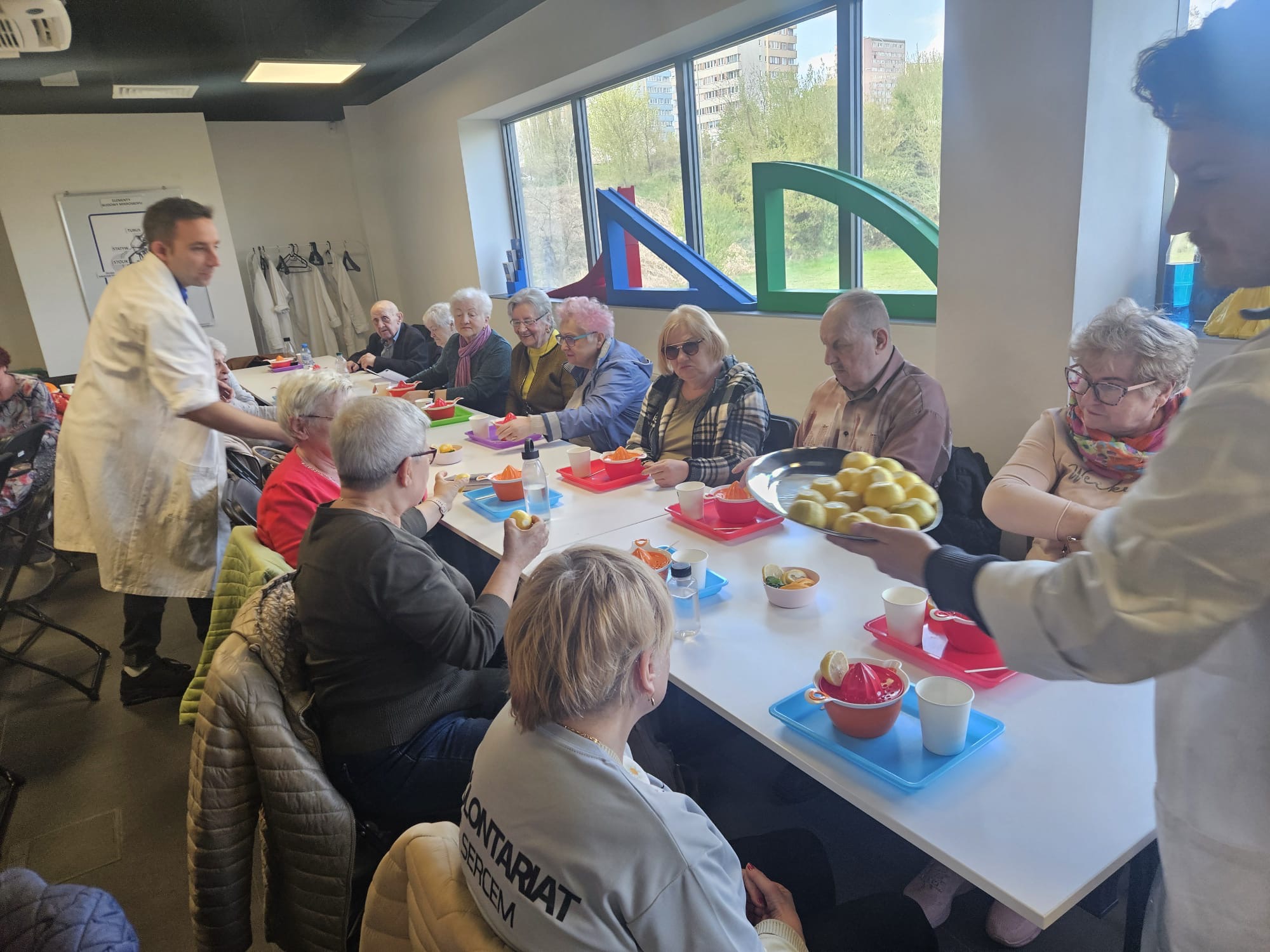 Seniorzy słuchają wykładu w sali warsztatowej