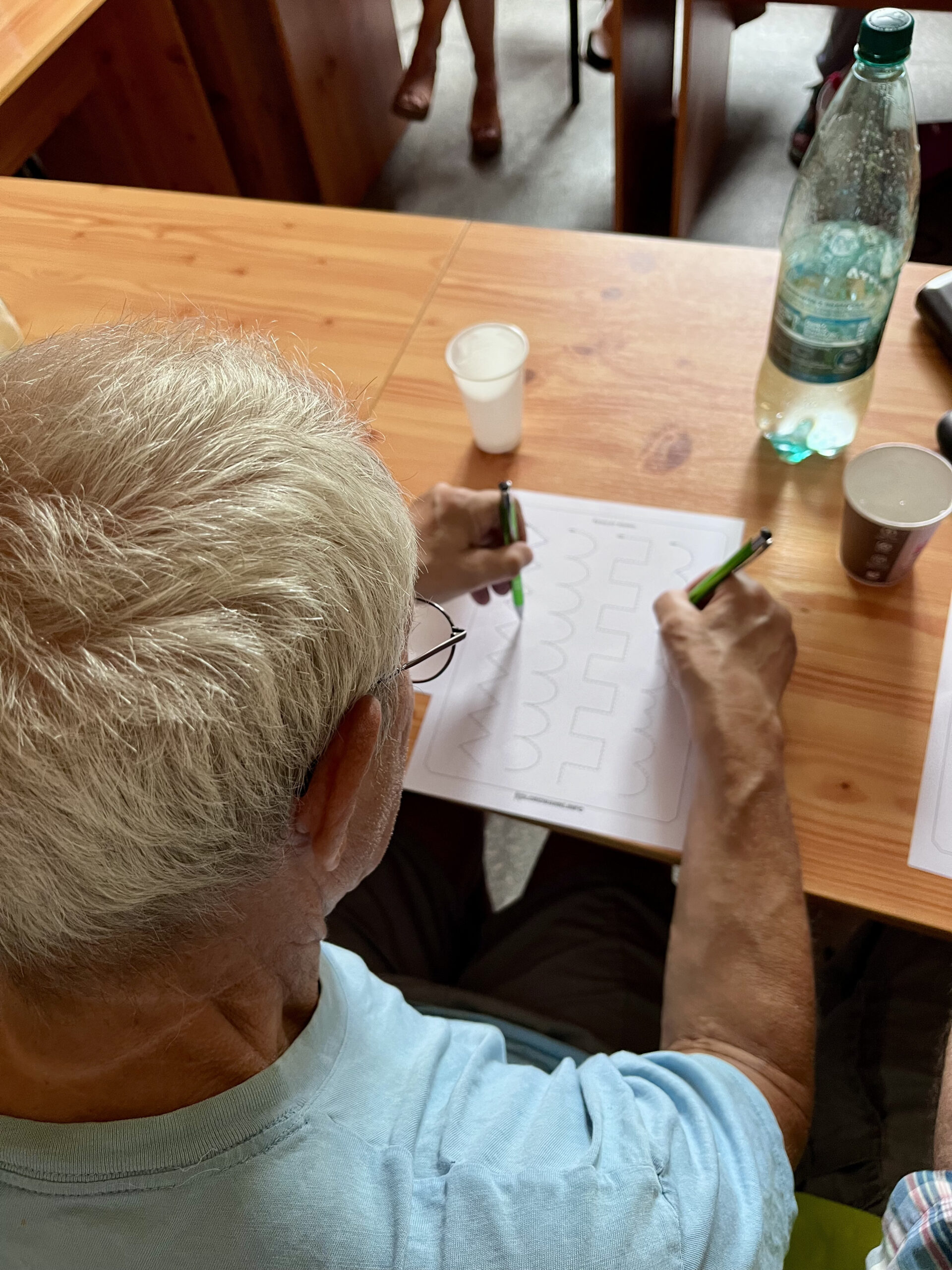 Zdjęcie przedstawia seniora rozwiązującego zadanie na kartce