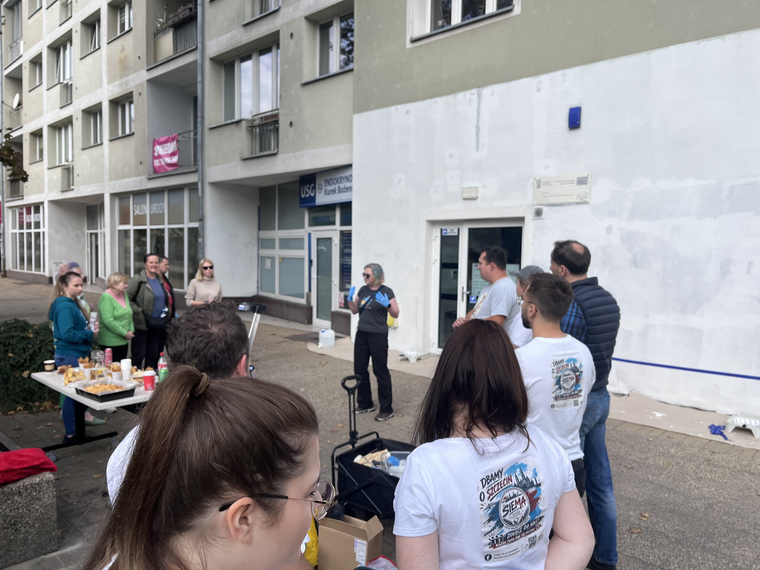 Zdjęcie przedstawia grupę ludzi pod Centrum Aktywności i Wolontariatu Seniorów
