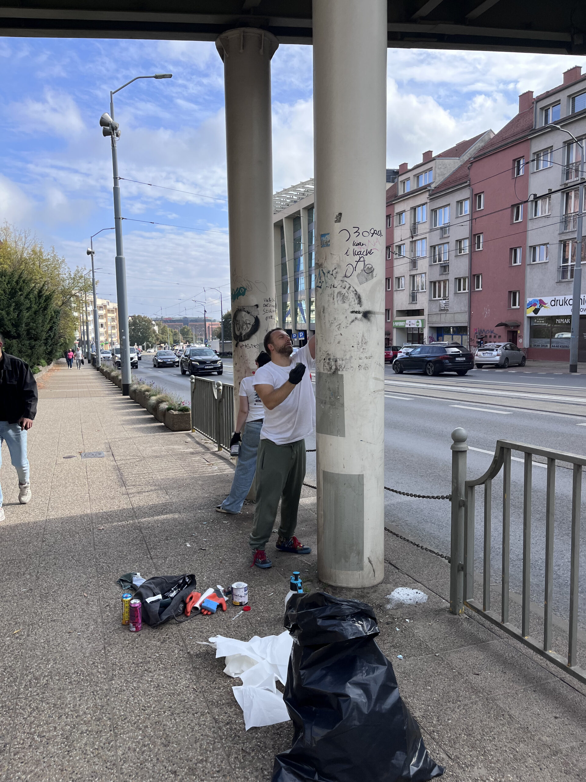 Zdjęcie przedstawia ludzi podczas prac porządkowych pod Centrum Aktywności i Wolontariatu Seniorów