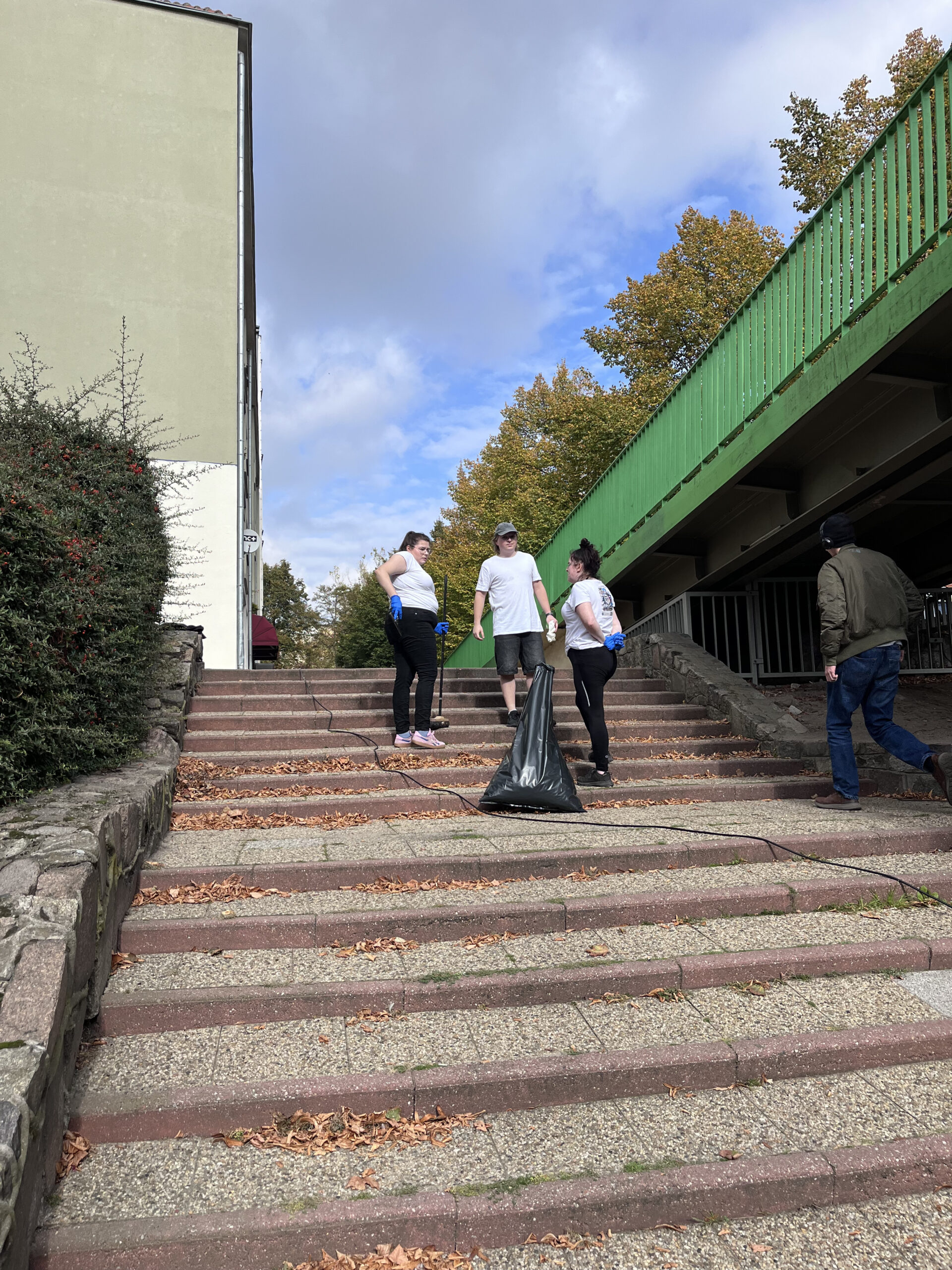 Zdjęcie przedstawia ludzi podczas prac porządkowych pod Centrum Aktywności i Wolontariatu Seniorów